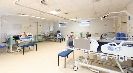 A four bay ward room, with beds, tables and seats in each bay.