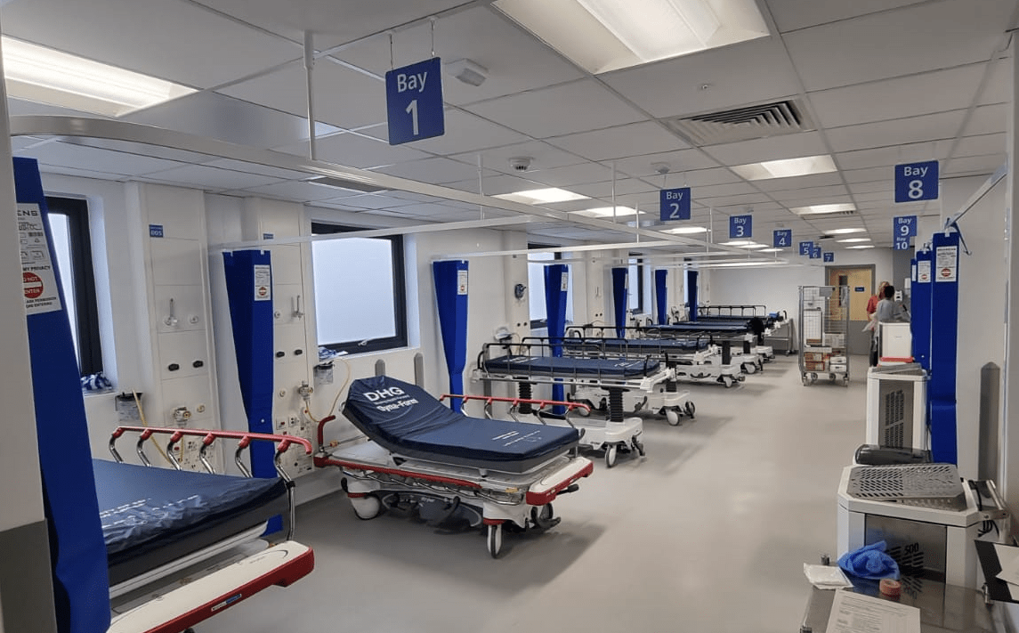 Inside the ambulance receiving centre, showing a row of hospital beds with curtains separating each bay.