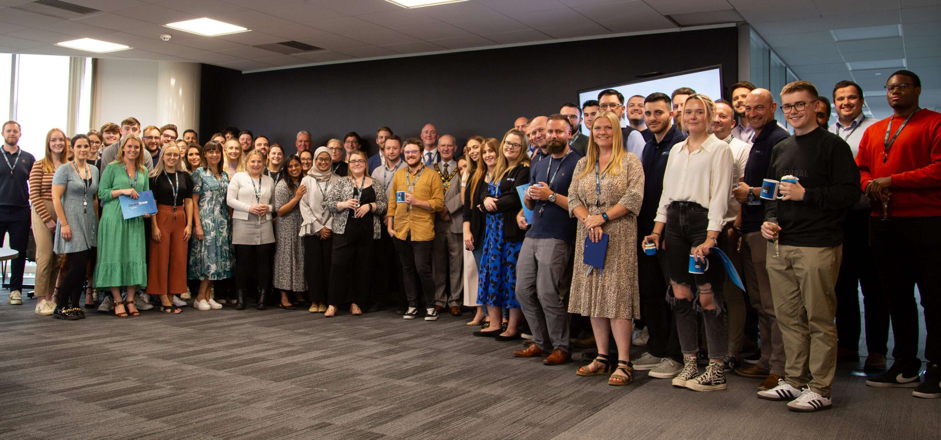 The Darwin Group HQ staff, all gathered in a group in the staff hub and smiling for the camera.