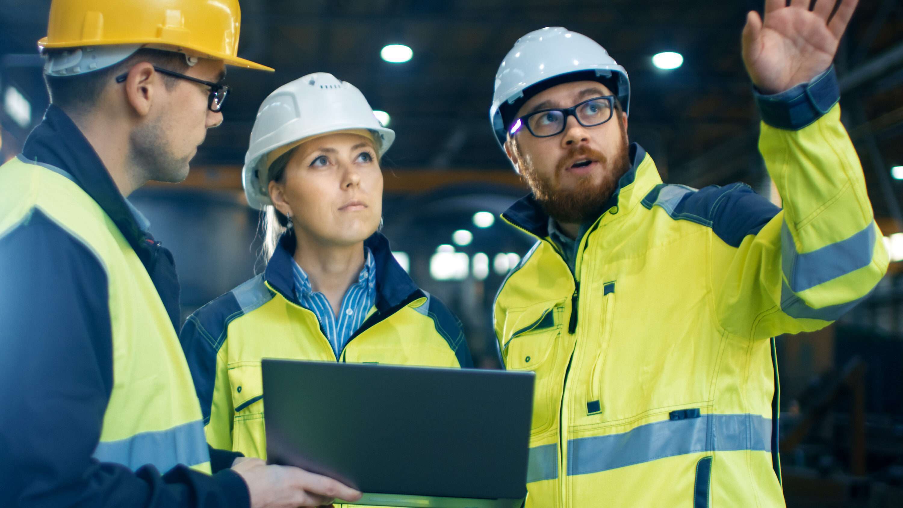 Three people in high-vis and PPE, one of them is holding a computer tablet.