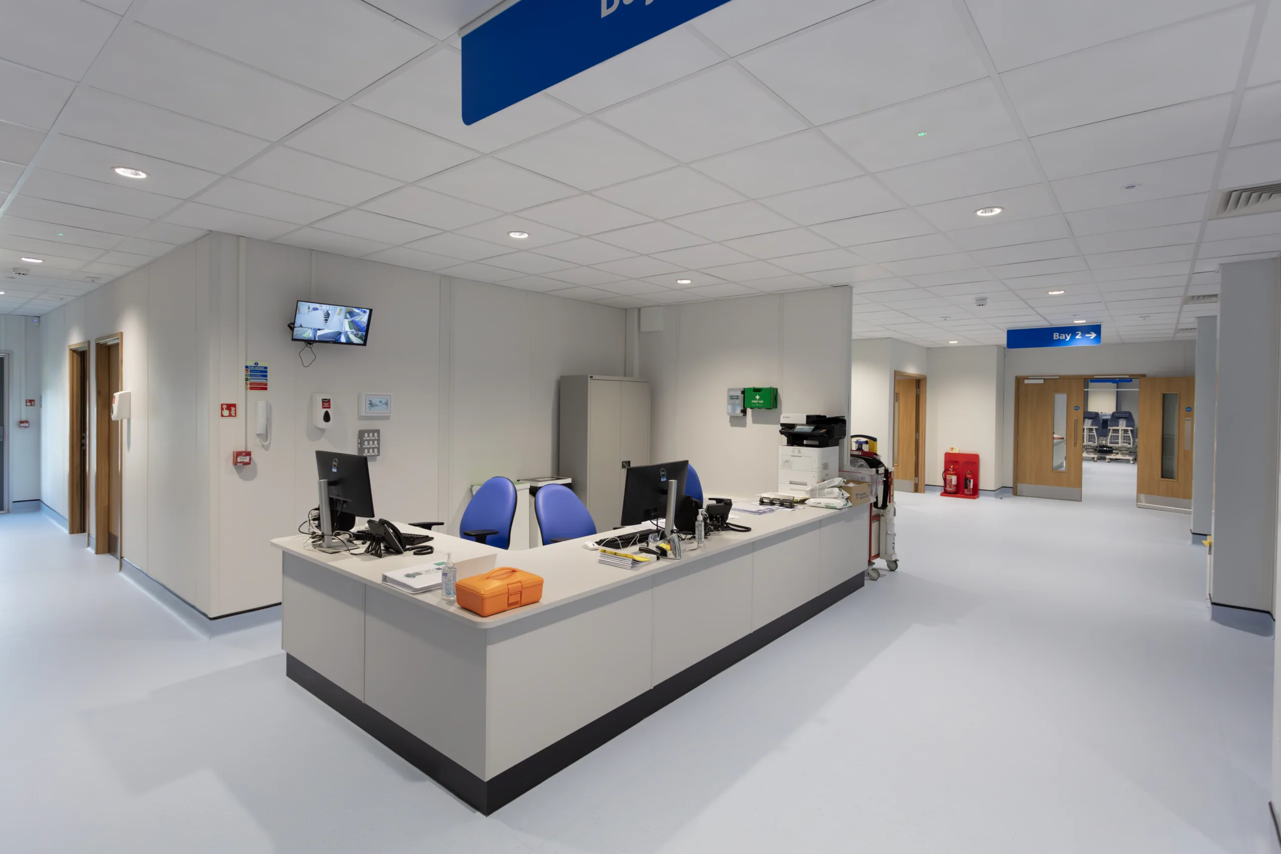 A photograph of the inside of Fareham Community Hospital, a Portakabin project. The photo shows a reception or nurse's station with a wide corridor leading away