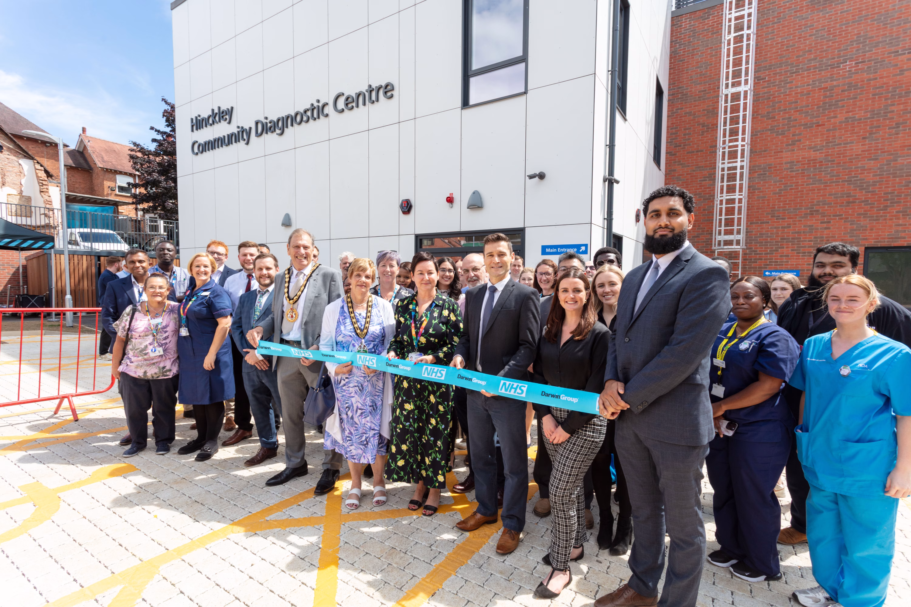 Group of people, including MP Dr Luke Shaw, holding a ceremonial ribbon outside the new Community Diagnostic Centre in Hinckley, Leicester