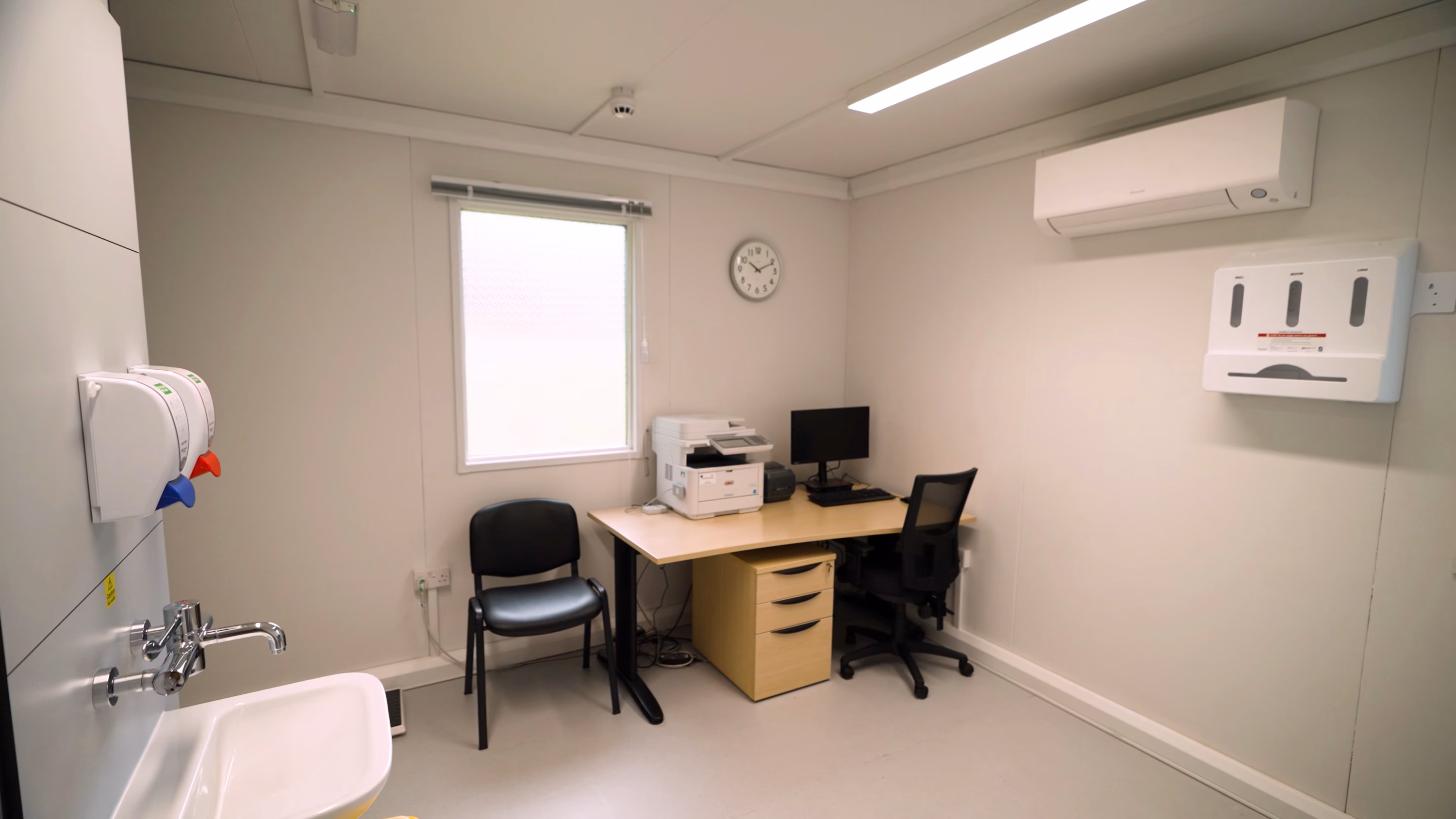 A GP consultation room, with a desk and patient examination bed