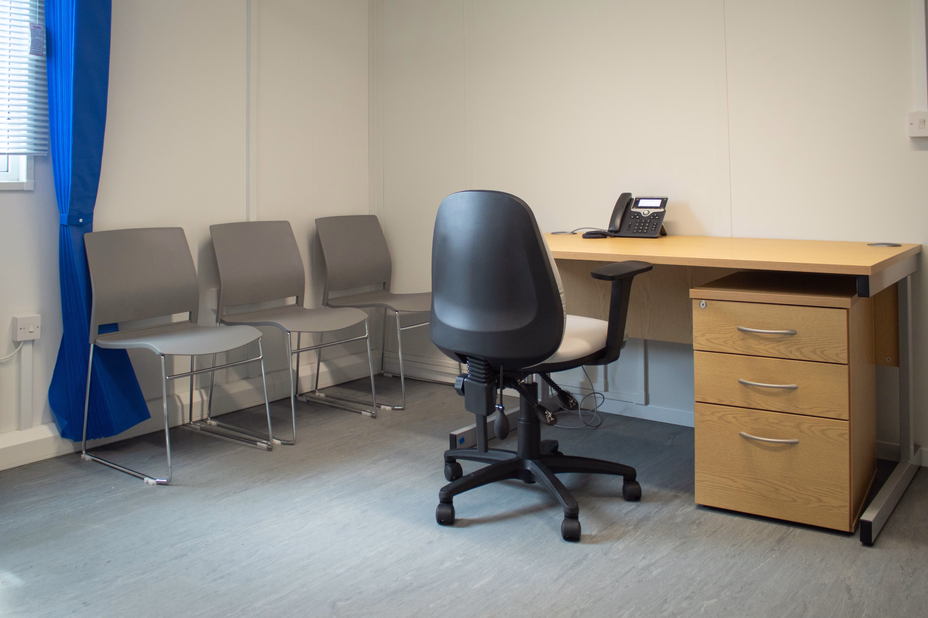 Healthcare consultation room showing desk and patient chairs